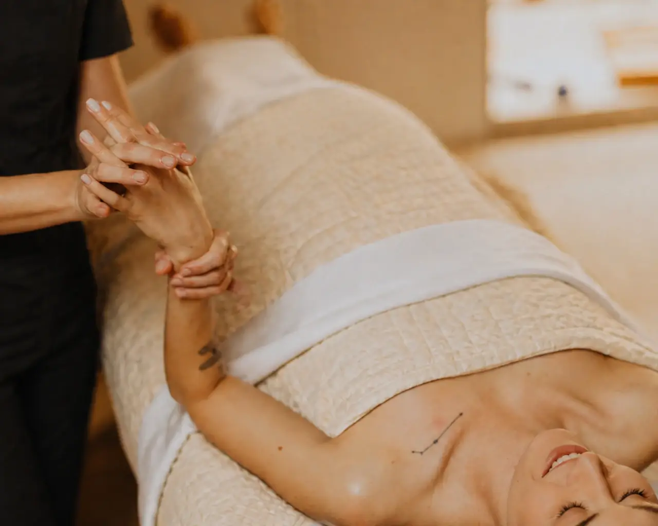 Folded white spa towels with a small ceramic dish of warm oil