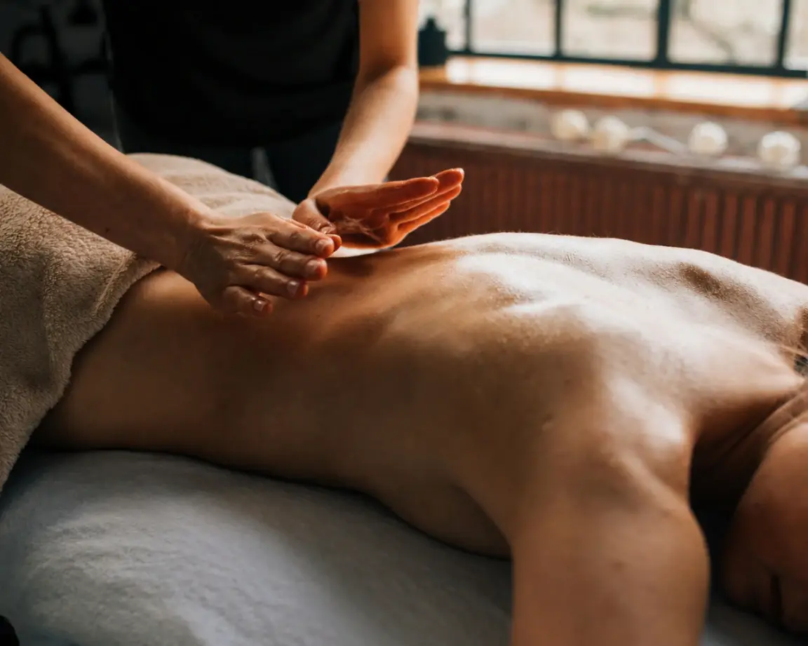 Calm in-room massage setup with white linens and warm oil in a sunlit Playa del Carmen interior