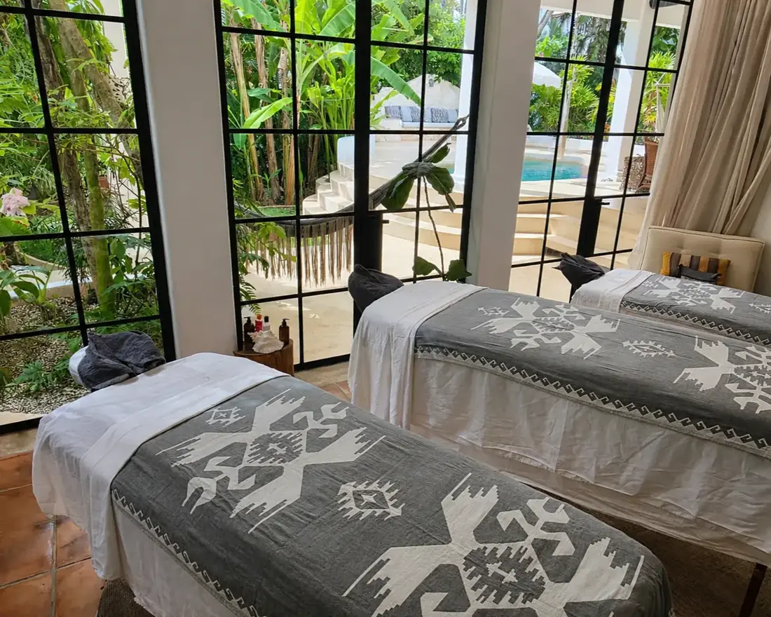 Group wellness retreat with three massage tables and white linens in a calm bright room