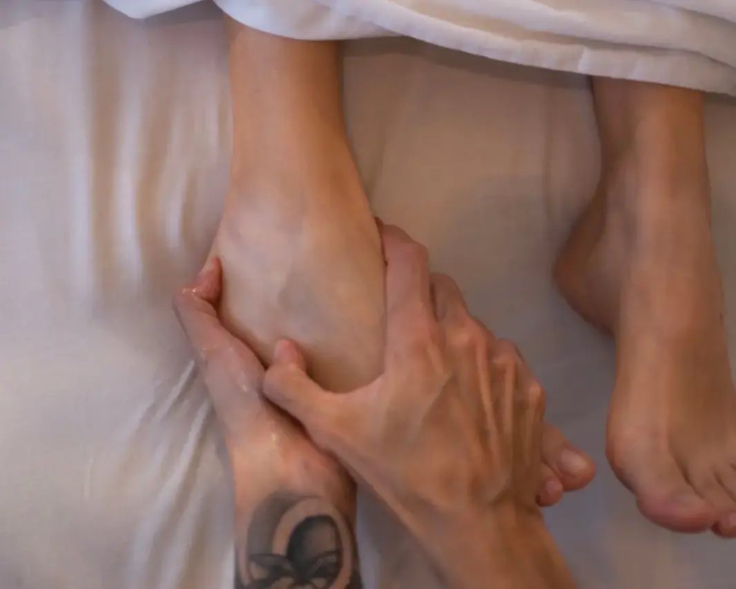 Bare feet resting on a folded white towel surrounded by smooth river stones