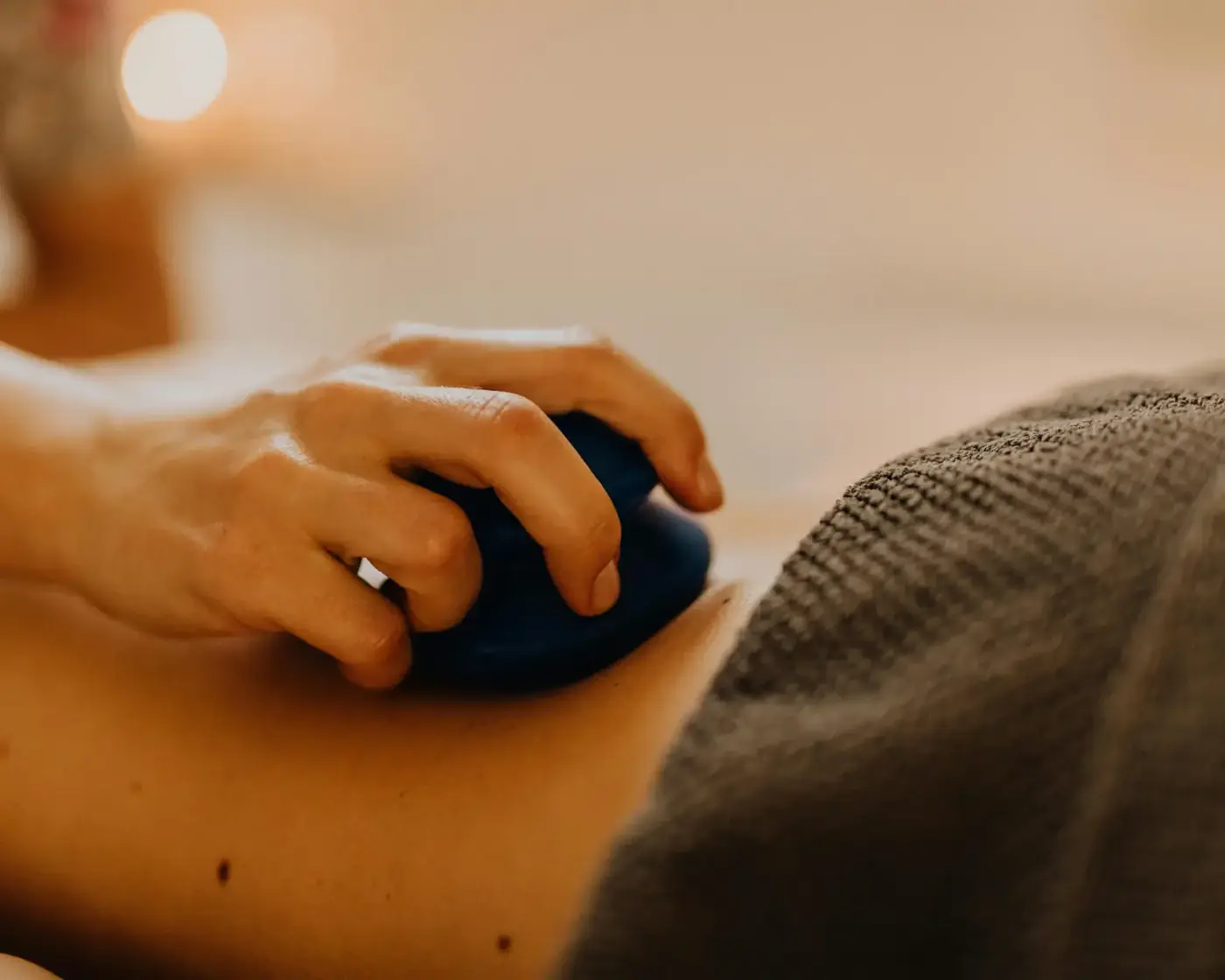 Stack of smooth dark river stones with a sprig of eucalyptus on white linen